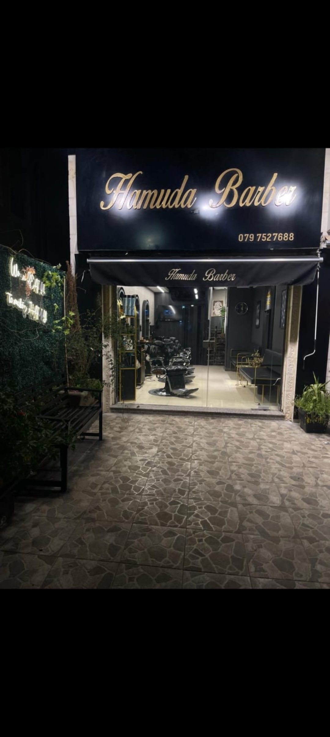 Hamuda Barber storefront lit up at night