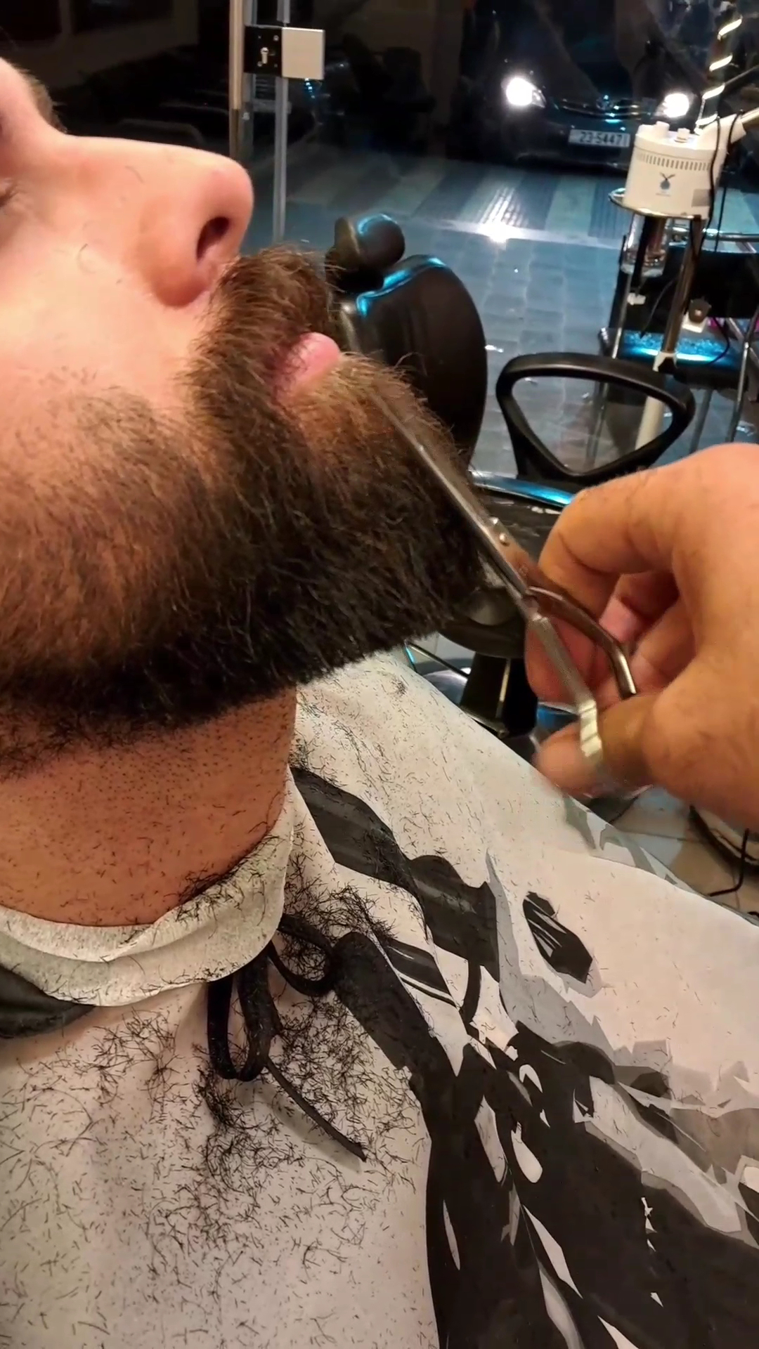 Close-up of a barber trimming a client's beard with scissors
