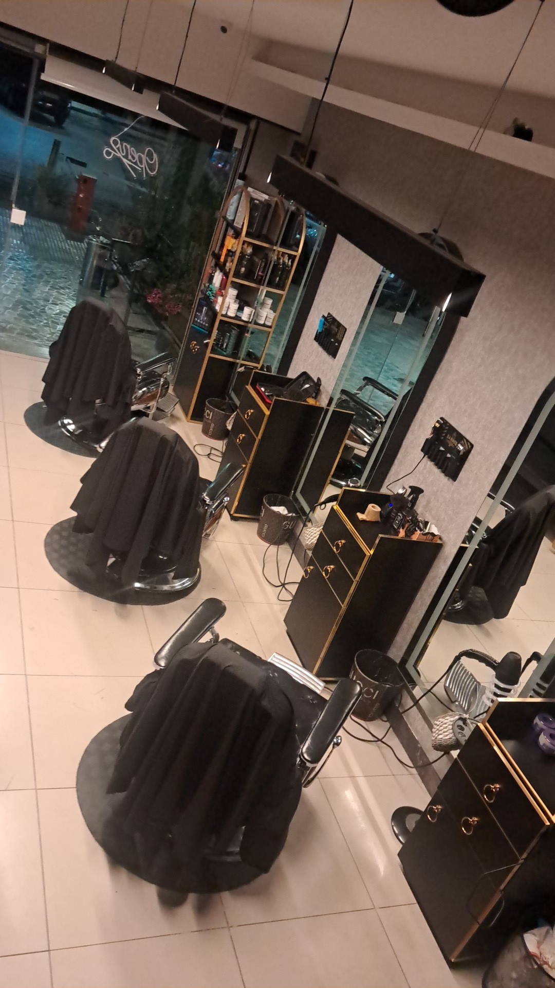 Row of black leather barber chairs and styling stations inside Hamuda Barber